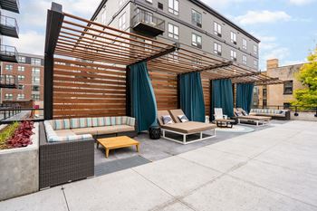 An outdoor patio with couches and chairs and a wooden canopy